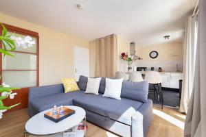 a living room with a blue couch and a kitchen at Le Marnois-Gare in Noisy-le-Grand