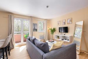 a living room with a couch and a tv at Le Marnois-Gare in Noisy-le-Grand