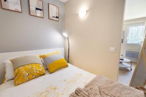 a bedroom with a bed with yellow and gray pillows at Le Marnois-Gare in Noisy-le-Grand