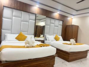 a bedroom with two beds with white sheets and yellow pillows at Surmila International Hotel in Āsansol