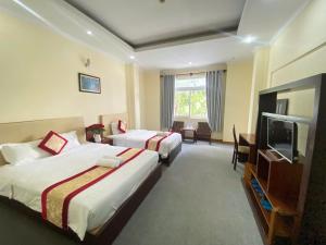a hotel room with two beds and a flat screen tv at Khách Sạn Á Châu Cần Thơ in Can Tho