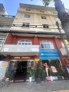 a building with a man standing in front of it at Khách Sạn Á Châu Cần Thơ in Can Tho