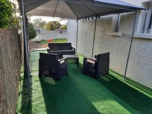 a patio with two chairs and an umbrella at Les chambres de Noëlla in LʼAiguillon-sur-Vie