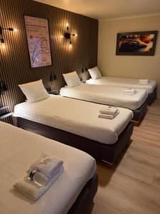a hotel room with three beds with towels on them at Hotel Le Relais de Pommard in Francorchamps