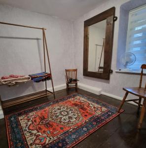 a room with a rug and a mirror and a chair at River Cottage in Llanbedr