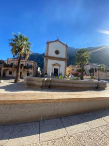 a building with a clock tower in front of a fountain at Sicilia Bedda Holiday Home in Cinisi