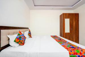 a bedroom with a white bed with colorful pillows at FabHotel Royal Garuda Palace in Bangalore