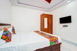 a white bedroom with a bed and a tv at FabHotel Royal Garuda Palace in Bangalore +24 photos
