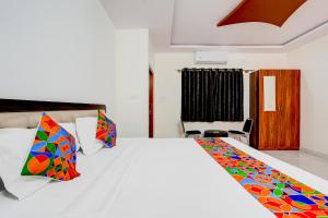 a bedroom with a white bed with colorful pillows at FabHotel Royal Garuda Palace in Bangalore