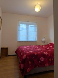 a bedroom with a red bed and a window at le chalet des remparts in Aywaille