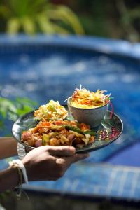 a person holding a plate of food with a bowl of food at Sundaras Infinity Jungle Resort & Spa in Dambulla