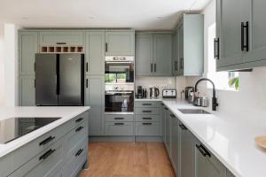a kitchen with white cabinets and a black refrigerator at Bluebell Barn - Cookswood in Holcombe