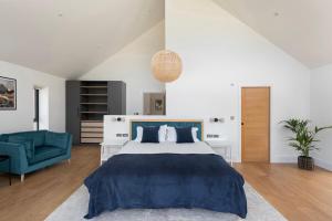 a bedroom with a large bed and a blue chair at Bluebell Barn - Cookswood in Holcombe