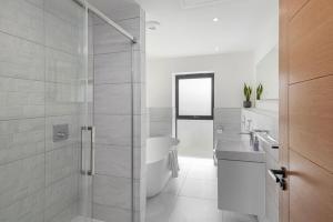a white bathroom with a tub and a sink at Bluebell Barn - Cookswood in Holcombe
