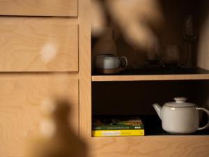 a person standing in a cabinet with a tea pot and books at Yarn - Milo Deluxe King Suite in Ballycastle