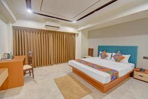 a hotel room with a bed and a desk and a desk at FabHotel New Moshi Grrand in Pune +24 photos