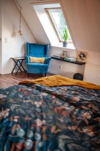 a attic bedroom with a bed and a blue chair at Art Apartment Sønderbygaard in Vinderup