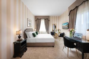 a bedroom with a bed and a desk with a laptop at Hotel Palazzo Borghini - Gruppo Estella Hotels in Florence