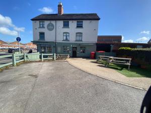 a white building with two benches in front of it at Town Centre House Sleeps 8 with parking in Stafford