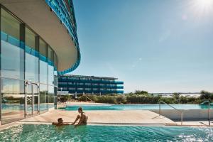 two people in a swimming pool next to a building at Falkensteiner Hotel & Spa Iadera in Zadar