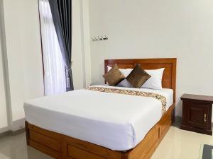 a bedroom with a bed with white sheets and a window at Guest House Primitif in Temon