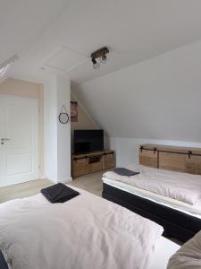 a bedroom with two beds and a flat screen tv at Landhaus Freche Socke in Buchhorst