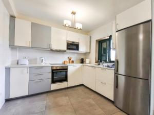a kitchen with white cabinets and a stainless steel refrigerator at Casa da Estação in Torre de Moncorvo