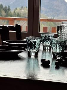 a table with four glass cups and plates on it at Sous l'Alpette en Chartreuse in Saint-Pierre-dʼEntremont