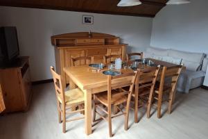 a wooden dining room table with chairs and a couch at Sous l'Alpette en Chartreuse in Saint-Pierre-dʼEntremont