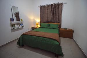 a bedroom with a green bed with a window at Vila_da_Montanha in Gravatá