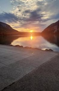 a sunset over a body of water with the sun setting at Le Cocon Du Lac in Nantua