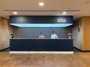 two people standing behind a counter in a lobby at YWCA Fort Canning in Singapore