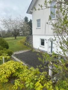 a white house with a garden in front of it at Ferienwohnung am Nurburgring in Welcherath