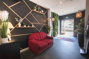a red chair in a living room with a wall at Hotel Mondial in Tours
