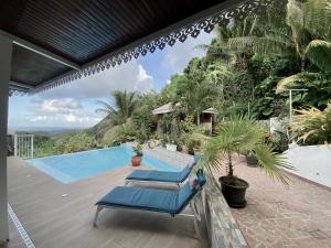 a patio with two blue lounge chairs next to a swimming pool at La Villa Rosier in Le François
