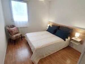 a bedroom with a bed and a chair and a window at L'appartement la rochebardière in Saint-Paul-lès-Dax