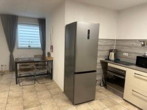 a kitchen with a stainless steel refrigerator and a table at Ferienwohnung am Nurburgring in Welcherath