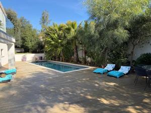 a swimming pool with two blue chairs next to a house at Bali 83 in Bandol