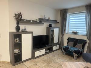 a living room with a tv and a chair at Ferienwohnung am Nurburgring in Welcherath