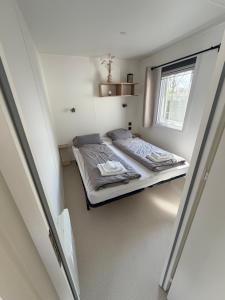 a small bedroom with a bed with a window at Strand chalet Makkum in Makkum +30 photos