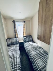 two beds in a small room with a window at SEA VIEW CARAVAN Disability friendly in Caister-on-Sea