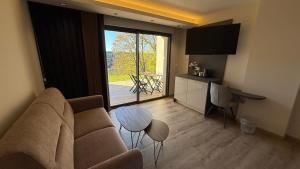 a living room with a couch and a table at La Rose du Lac Hôtel Appart' in Coucouron