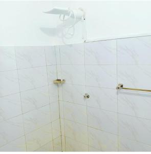 a bathroom with a shower with white tiles at kandys place in Watamu