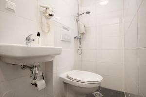 a white bathroom with a toilet and a sink at King's Inn City Hostel Alkmaar in Alkmaar +31 photos