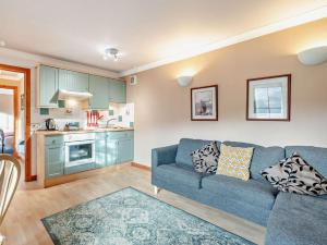 a living room with a blue couch and a kitchen at 1 Bed in Crieff oc-45288 in Saint Fillans +8 photos