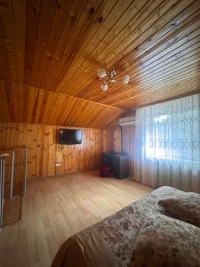 a bedroom with a wooden ceiling with a bed and a television at Санаторій Сонячний in Verbki