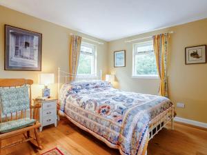 a bedroom with a bed and a chair and two windows at 1 Bed in Ardgay oc-89058 in Culrain