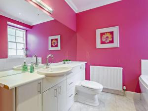 a bathroom with pink walls and a toilet and a sink at 3 Bed in Dingwall oc-ca388 in Cononbridge +9 photos