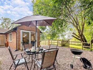 a table and chairs with an umbrella and a grill at 2 Bed in Crewe oc-83192 in Audlem