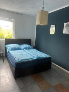 a bed in a bedroom with a blue wall at Ferienwohnung am Nurburgring in Welcherath